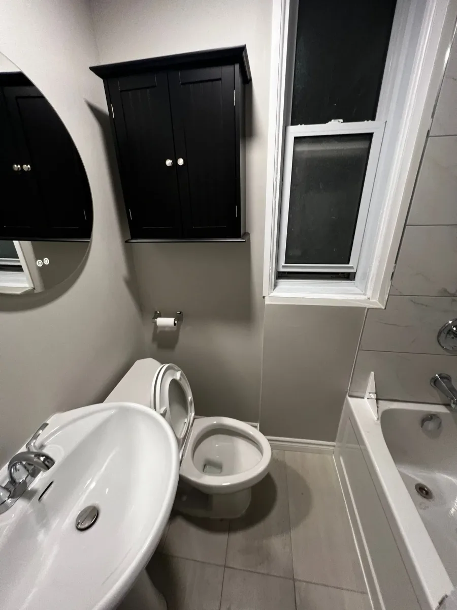 Wall-mounted cabinet above the toilet beside the sink and bathtub in Meiju’s compact bathroom project gallery.