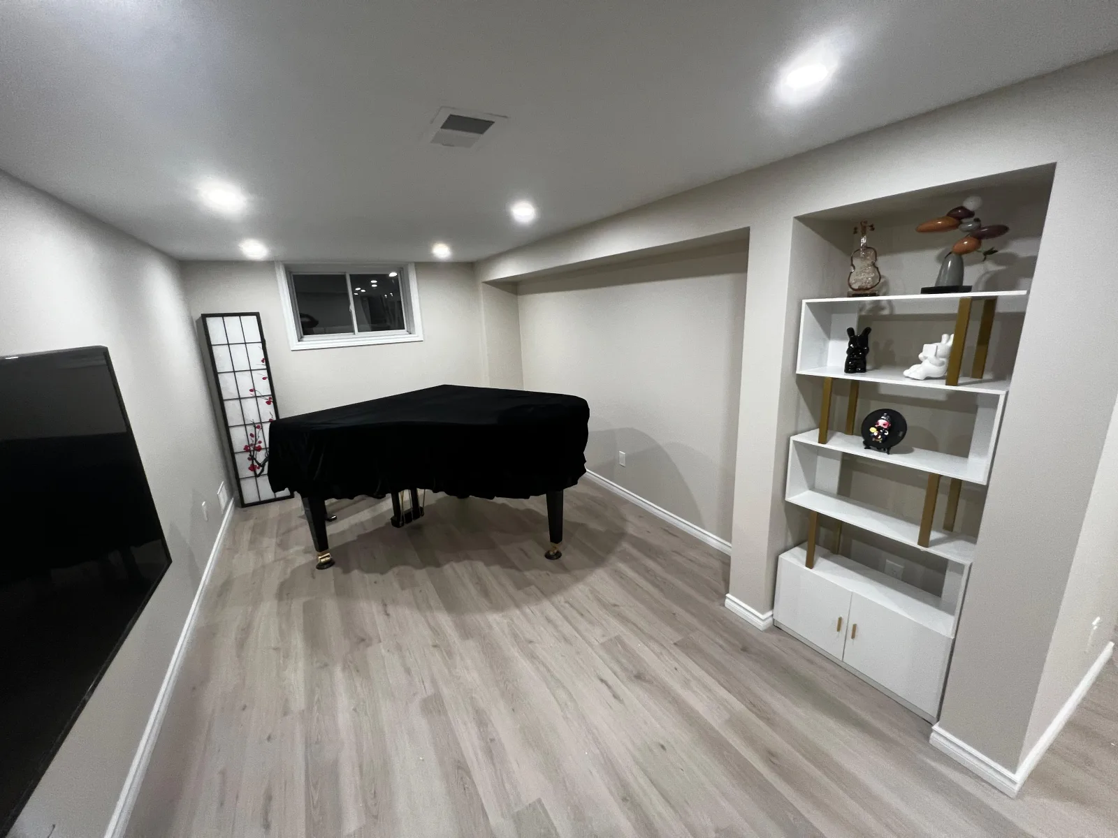 Completed basement living room with piano and built-in shelving